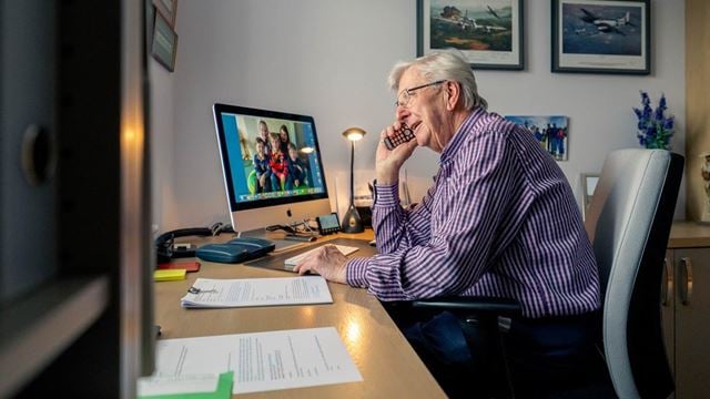 a person sitting at a desk with a computer and papers