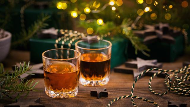 Two shot glasses of 'Christmas pudding vodka' on a festive decorated table.