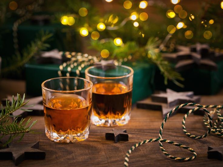 Two shot glasses of 'Christmas pudding vodka' on a festive decorated table.