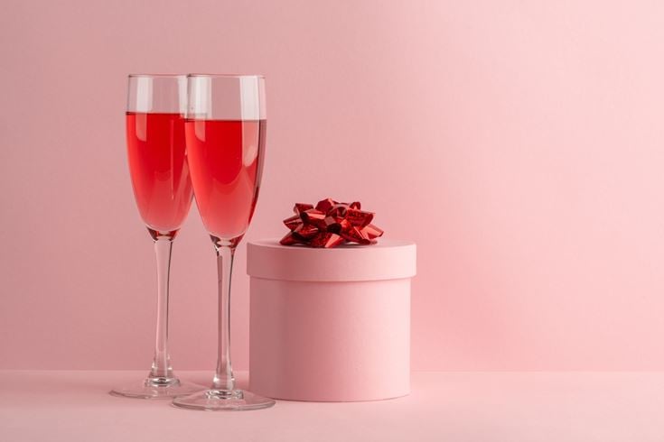 Two glasses of red prosecco based cocktails next to a present.