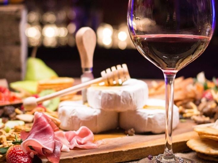 a glass of wine next to a plate of desserts