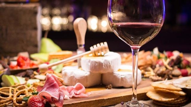 a glass of wine next to a plate of desserts