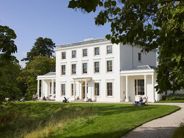 a white building with a lawn and trees in front of it