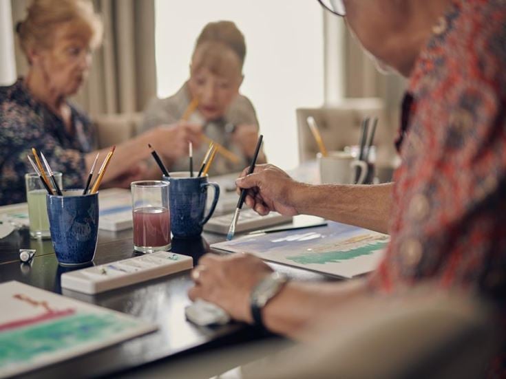 a group of people sitting at a table writing on paper