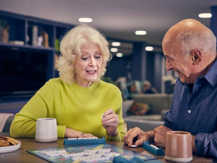 a man and a woman sitting at a table playing a board game