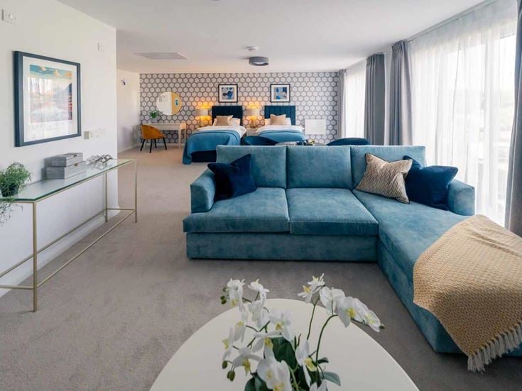 a large living room with a blue couch and a white table