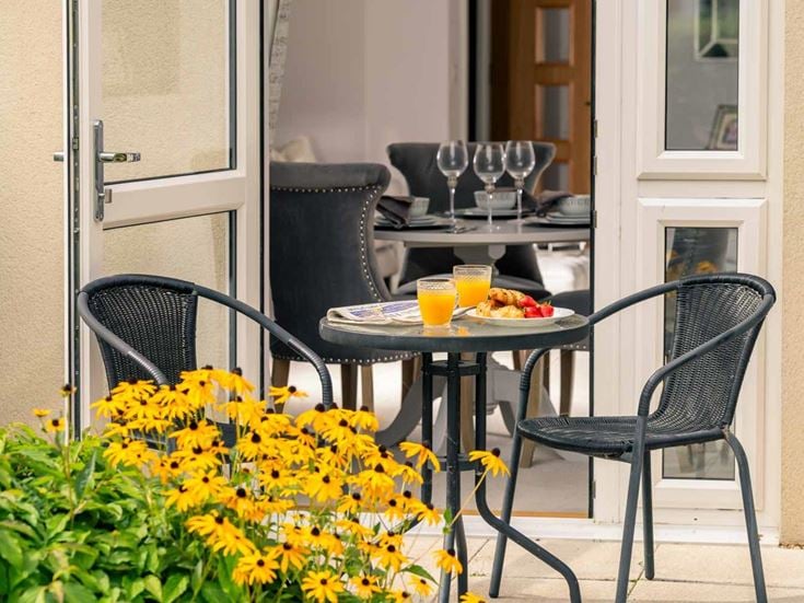 a table with a plate of food and a glass of juice on a patio
