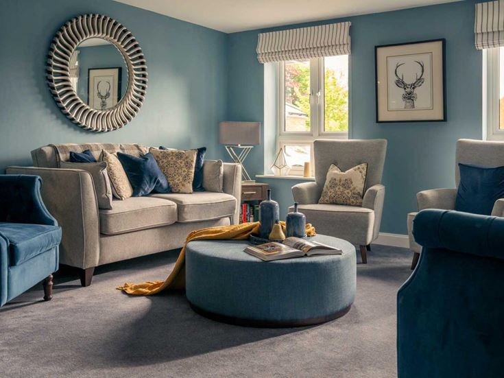 a living room with blue chairs and a round mirror
