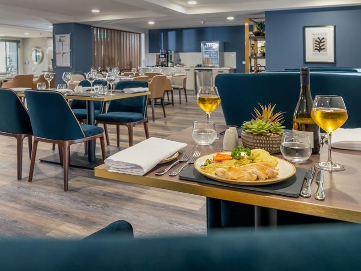 a dining table with a plate of food and wine glasses