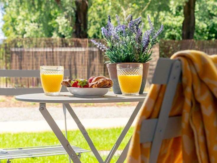 a table with a glass of juice and a bag of fruit on it