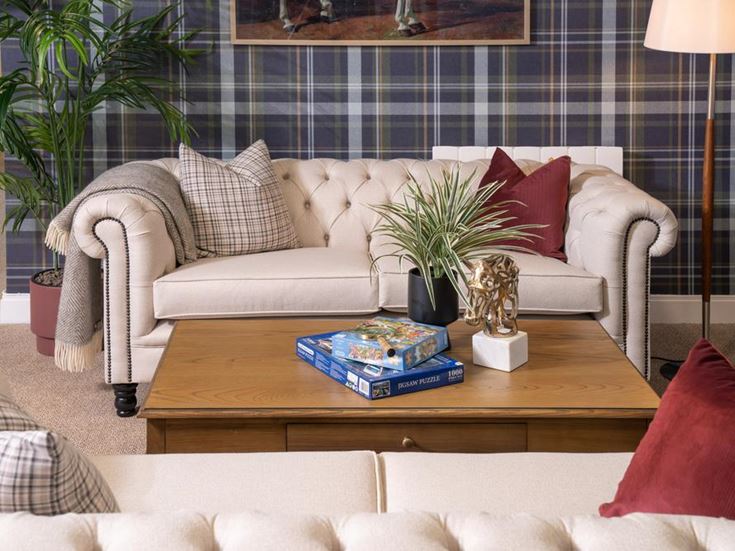 a white couch with a table and a coffee table with a book and a plant on it