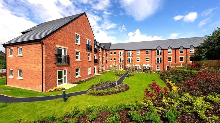a brick building with a garden in front of it