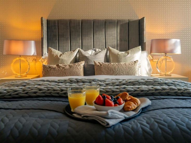 a bed with a tray of fruit and drinks on it