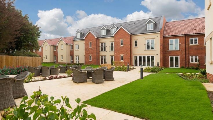 a brick building with a green lawn