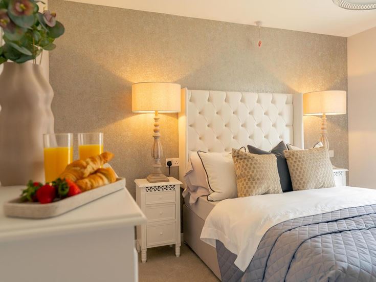 a bed with a white bed and a white table with a white table and a lamp and a