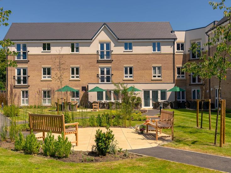 a large house with a lawn and benches in front of it