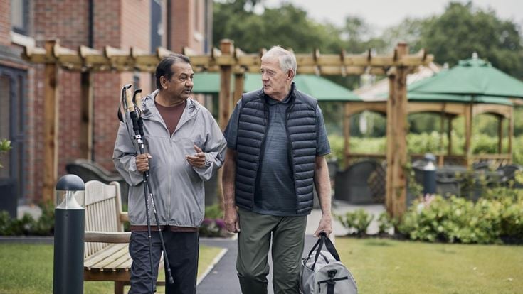 a couple of men walking down a sidewalk holding a pair of canes