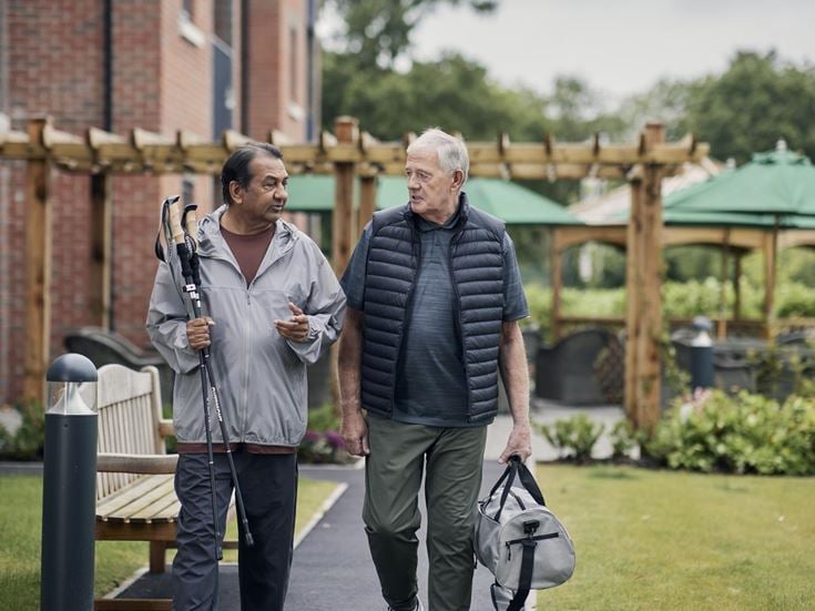 a couple of men walking down a sidewalk holding a pair of canes
