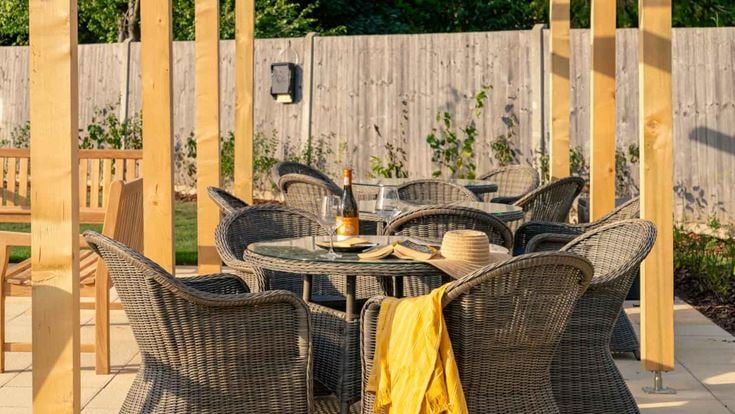 a table set with chairs and a wood fence