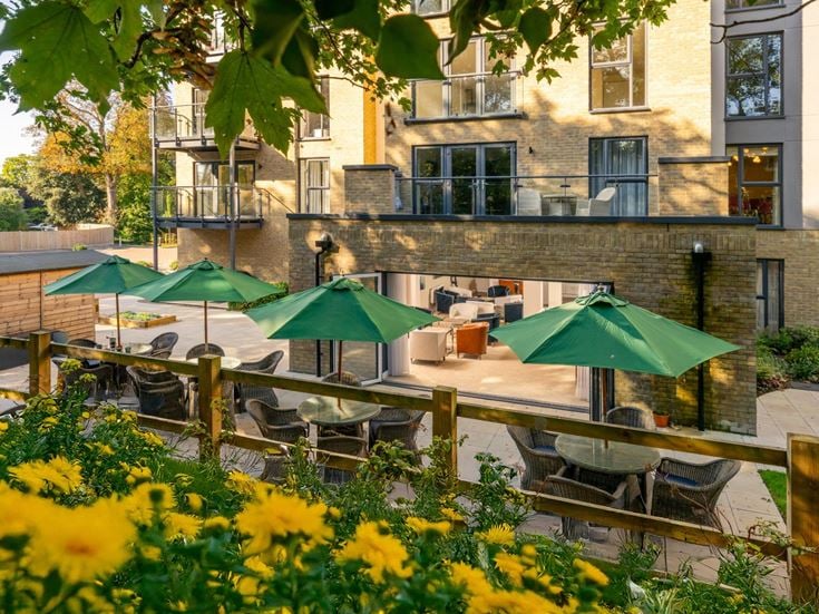 a patio with tables and chairs and umbrellas in front of a building