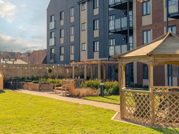 a backyard with a fence and a lawn and a building