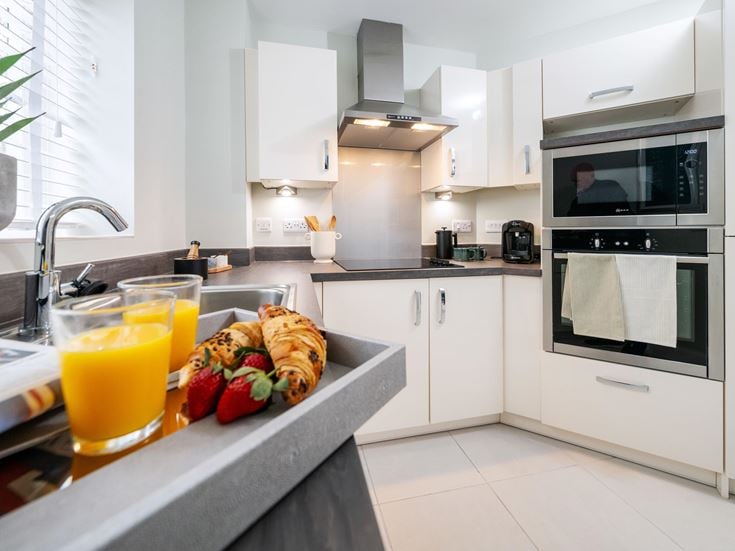 a kitchen with white cabinets and a counter top with fruit on it