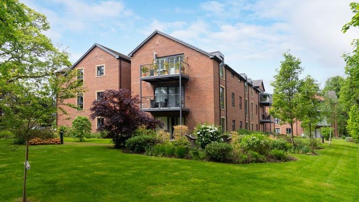 a brick building with trees and grass