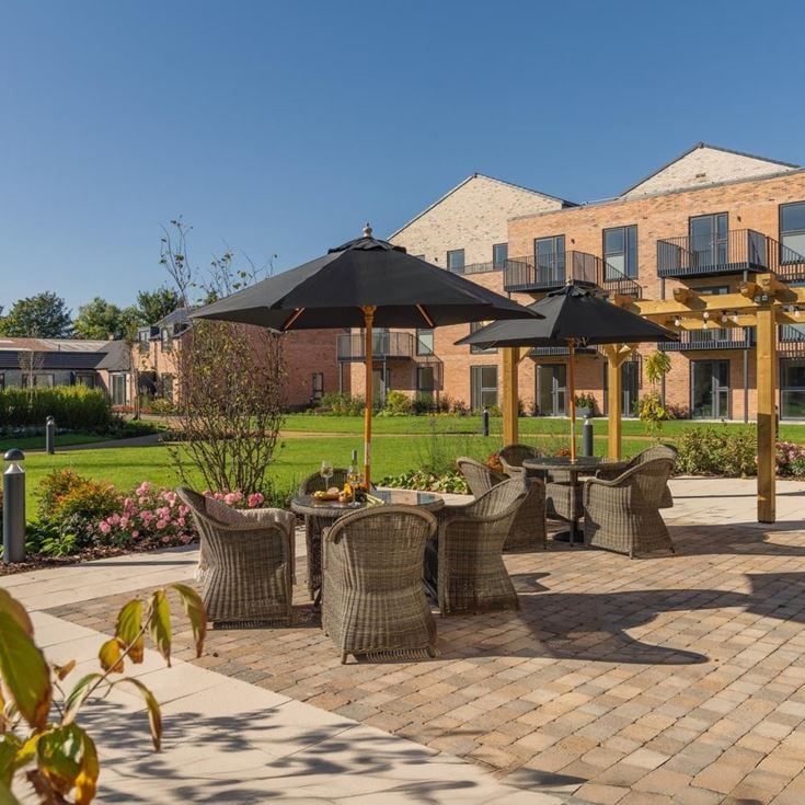 a brick patio with umbrellas and chairs in front of a building