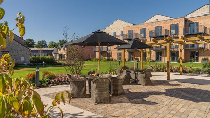 a brick patio with umbrellas and chairs in front of a building