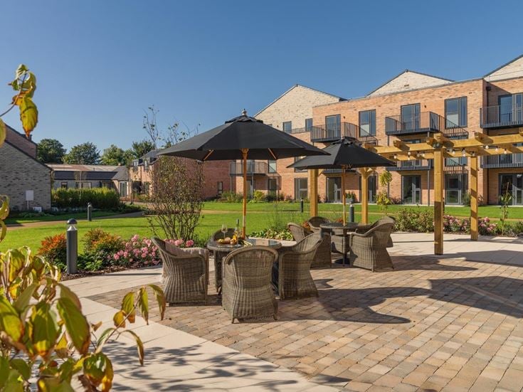 a brick patio with umbrellas and chairs in front of a building