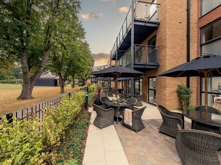 a patio with tables and chairs and umbrellas next to a building