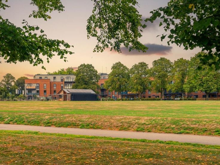 a grassy field with buildings in the background