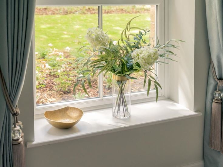 a vase of flowers sits on a window sill