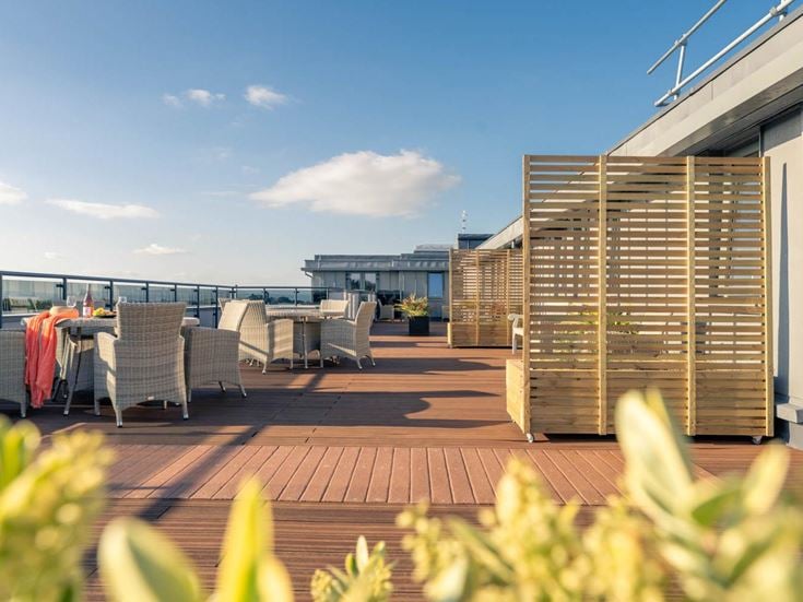 a deck with chairs and tables on it next to a body of water
