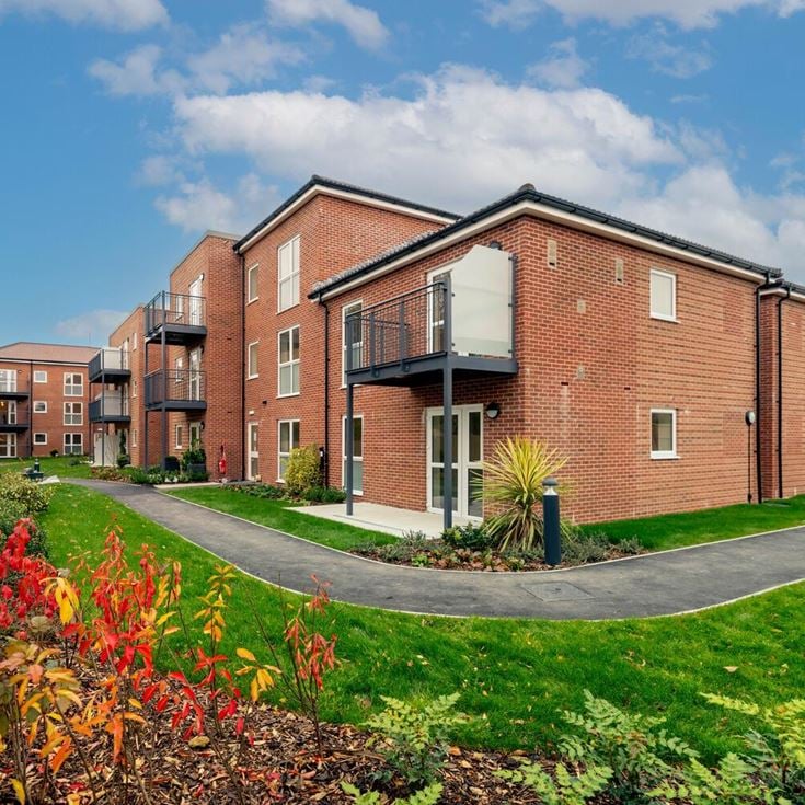 a brick building with a fence and a lawn in front of it