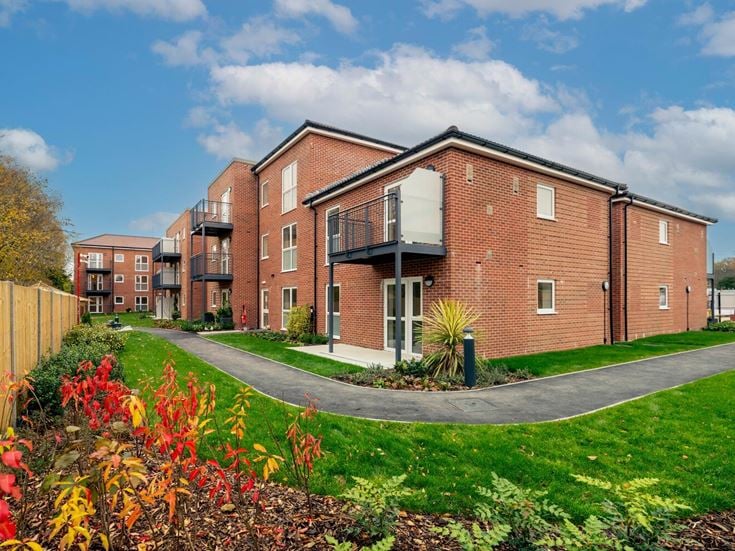 a brick building with a fence and a lawn in front of it
