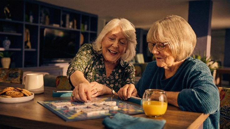 a couple of women sitting at a table with food and drinks