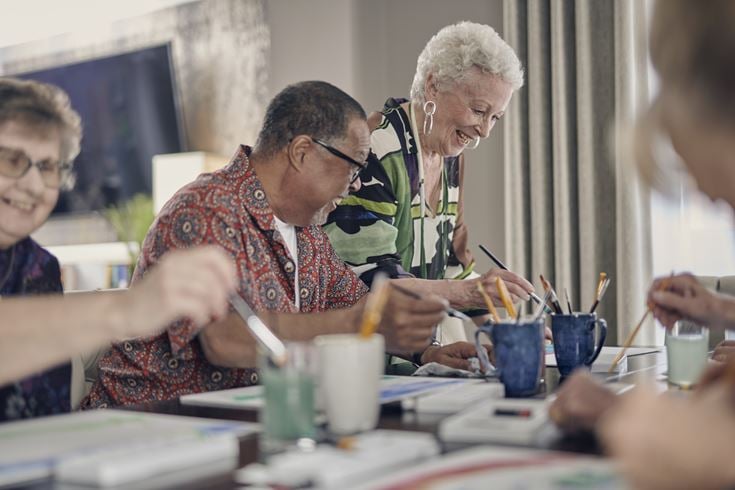 A group of retired people sat together while painting and crafting.