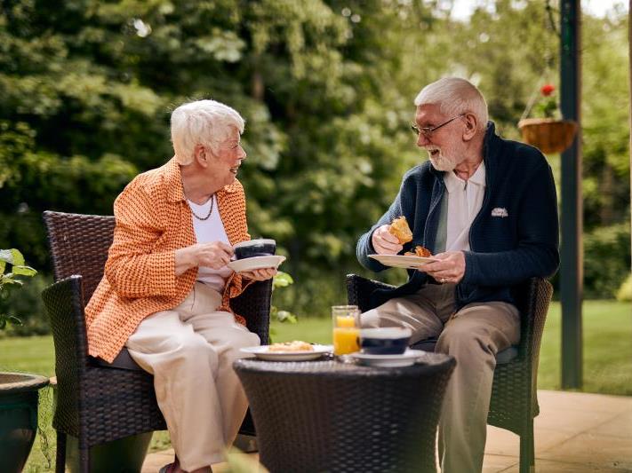 a couple of old people sitting at a table outside