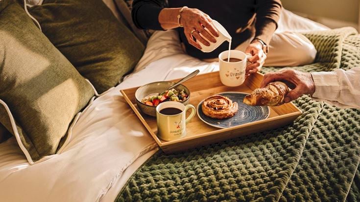 a tray of food and coffee on a bed