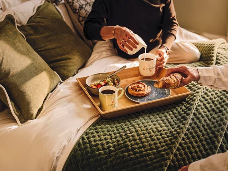 a tray of food and coffee on a bed
