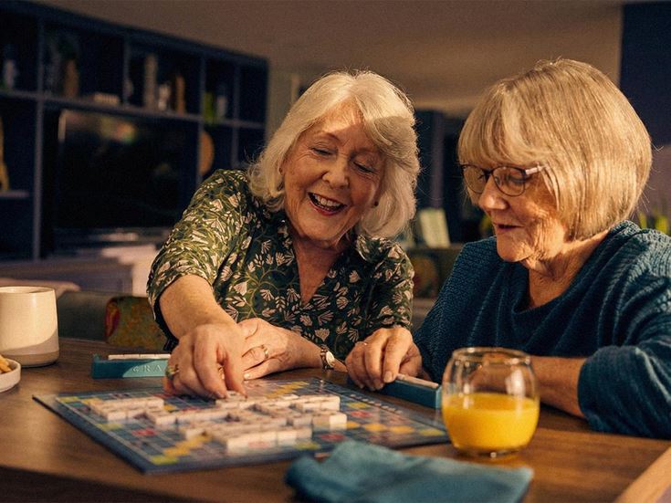 2 woman playing scrabble in the community lounge at a McCarthy & Stone retirement development