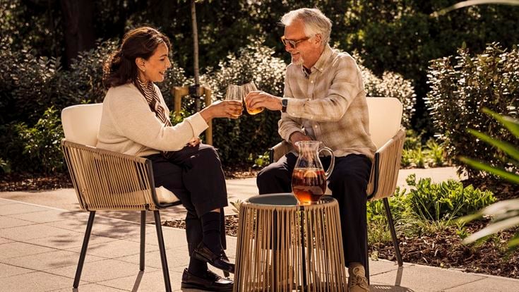 a man and woman sitting on a bench with a drink