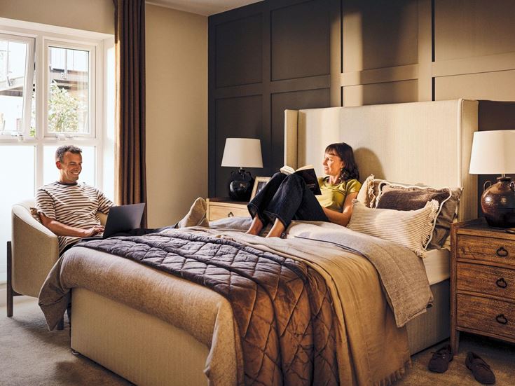 a man and a woman sitting on a bed with a laptop