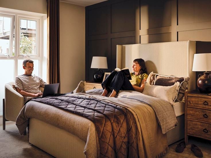 a man and a woman sitting on a bed with a laptop