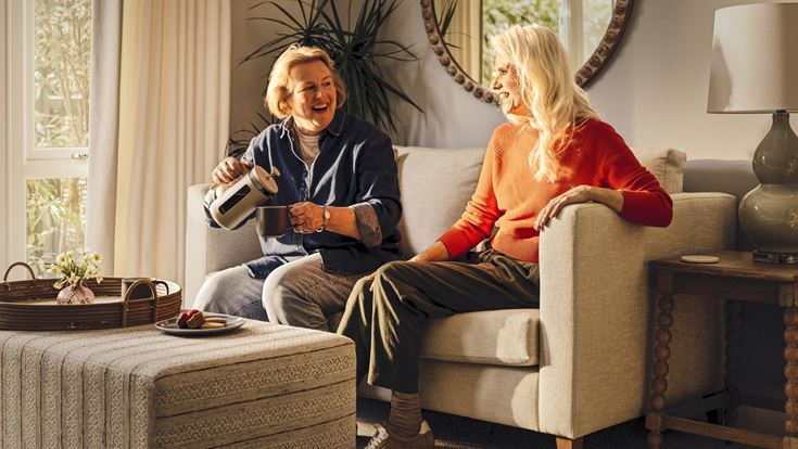 a woman sitting on a couch with a woman sitting on a chair
