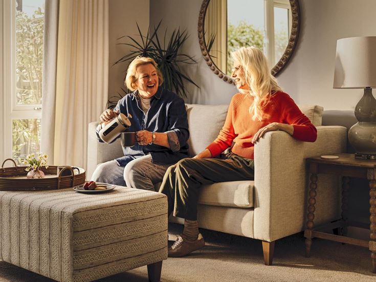 a woman sitting on a couch with a woman sitting on a chair