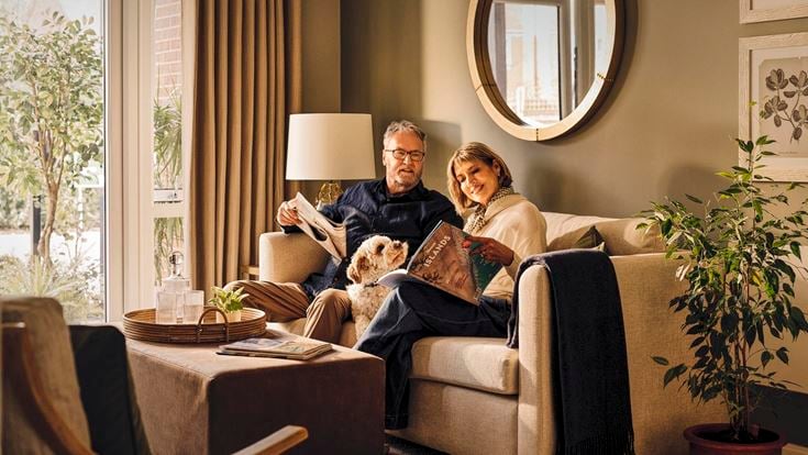 a man and woman sitting on a couch with a dog