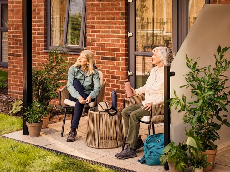 a couple of women sitting on a bench outside a building