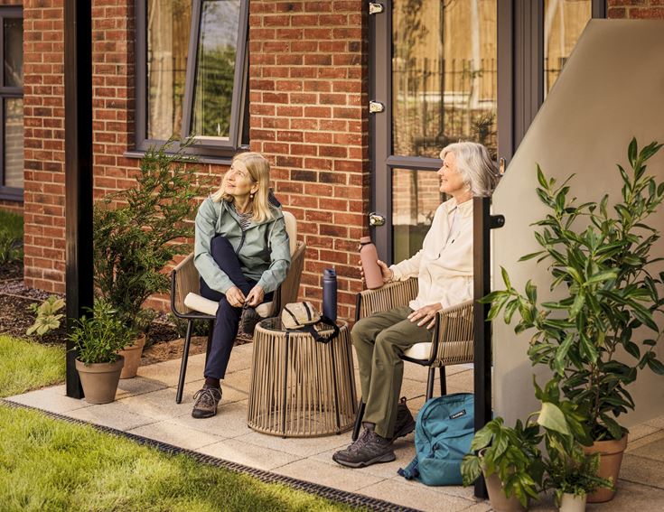 Two older ladies relax on their patio.